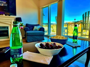 Una mesa de comedor con un tazón de cerezas, una botella de refresco y un tazón de palomitas de maíz.