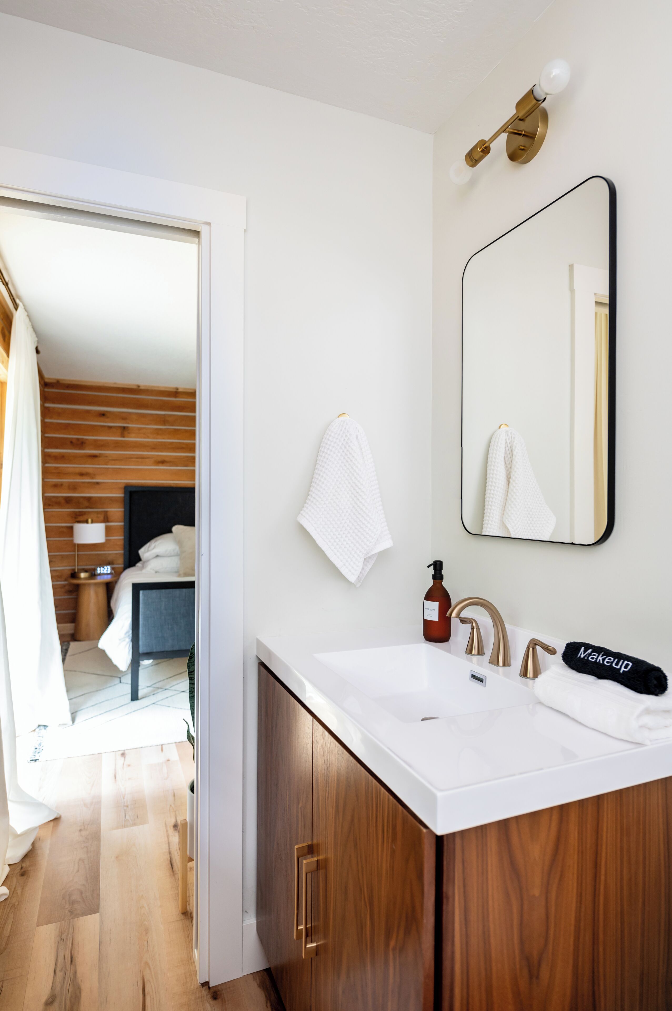 A modern bathroom with a white sink, wooden cabinets, and a large mirror.