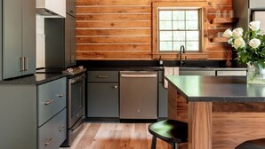 Una cocina moderna con paneles de madera, una isla central, taburetes de bar y un ventanal con vistas.