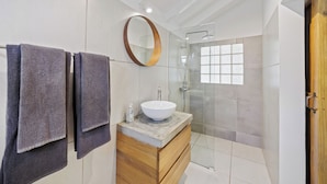 A modern bathroom with a large mirror, a vessel sink, and a glass-enclosed shower.