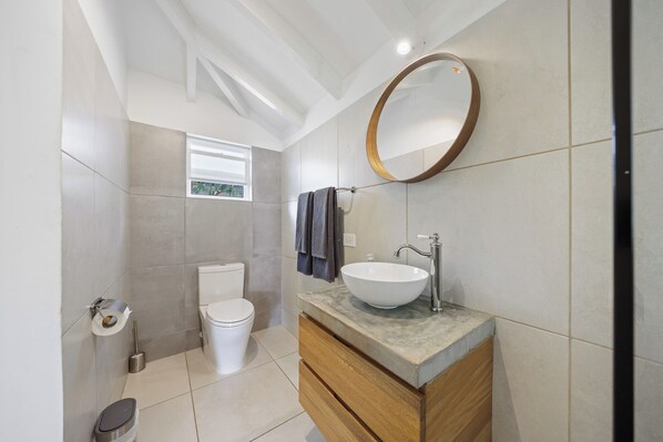 Une salle de bain moderne avec des toilettes, un lavabo et un miroir.