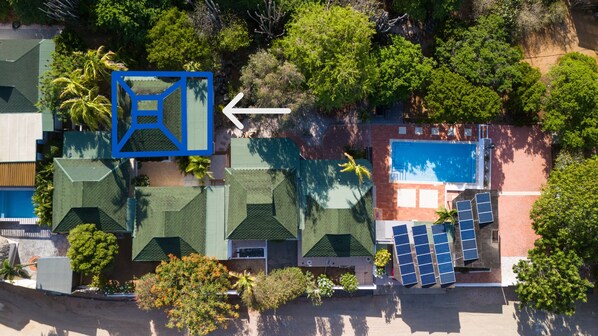 An aerial view of a resort with a swimming pool, sun loungers, and a large blue structure.