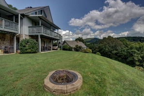 A two-story house with a balcony, a stone foundation, and a well-maintained lawn.