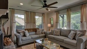 A living room with two grey sofas, a glass coffee table, and a ceiling fan. - Golden Bear- lovely one bedroom with fireplace (Sky Valley)