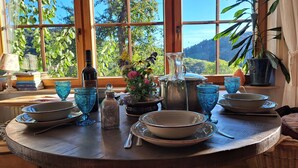 A dining table set with blue glassware, plates, and a bottle, with a scenic view through large windows. - Gemütliche Waldrandlage Badenweiler Sehringen (Badenweiler)
