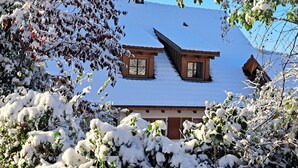 A wooden house with a sloped roof and dormer windows, surrounded by snow-covered trees and bushes. - Gemütliche Waldrandlage Badenweiler Sehringen (Badenweiler)