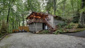 Uma cabana com um deck de madeira, área de estar externa e escadas que levam à entrada.