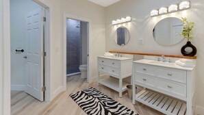 Un baño moderno con dos lavamanos, un espejo y una ducha.