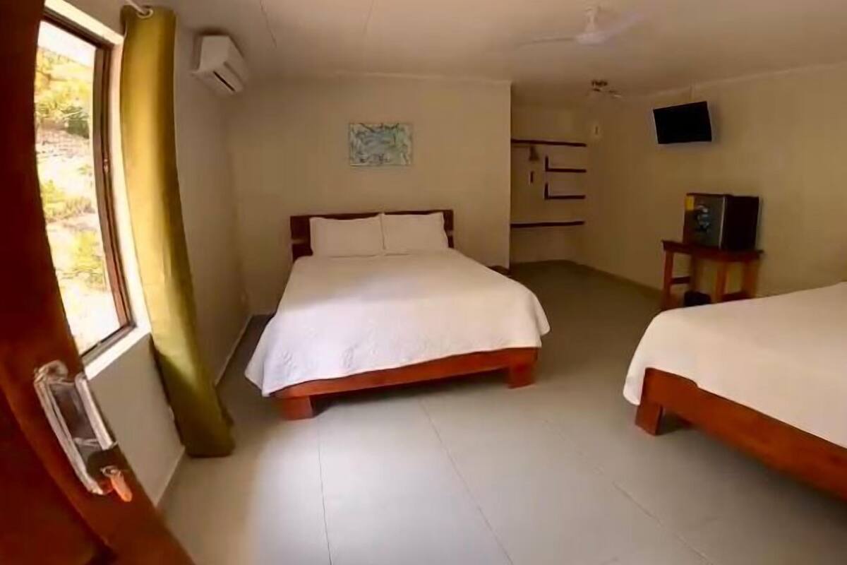 Een kamer met twee bedden, een televisie en een klein tafeltje.