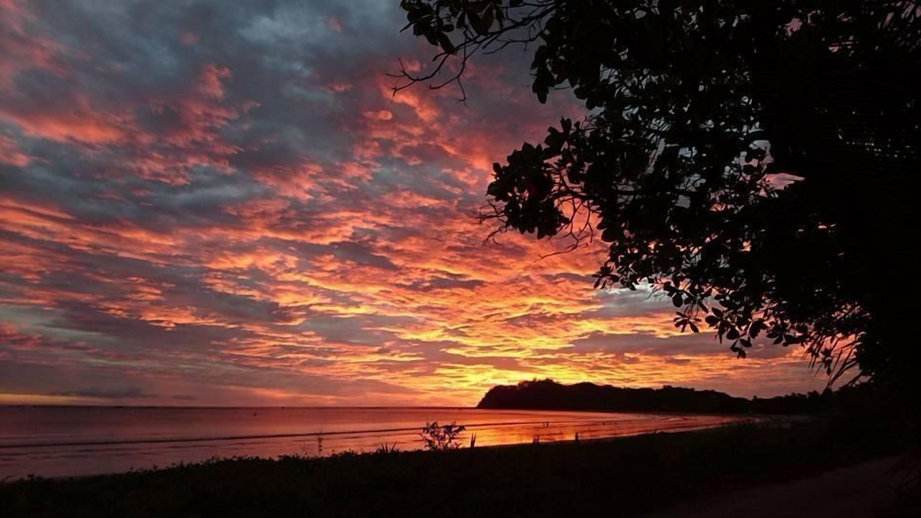 Atardecer sobre un paisaje costero con la silueta de una tierra distante.