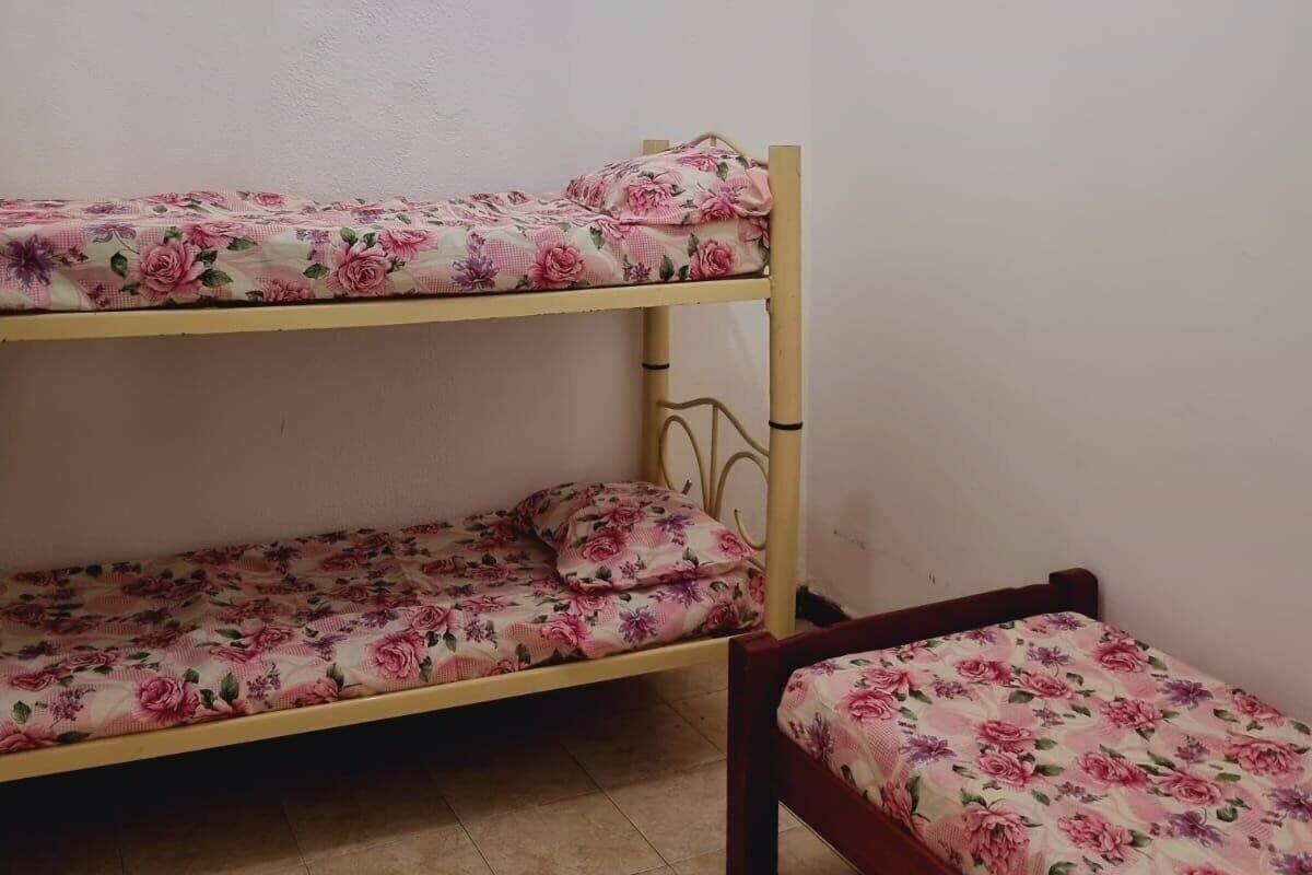 Una cama litera con ropa de cama floral en una habitación con paredes lisas.