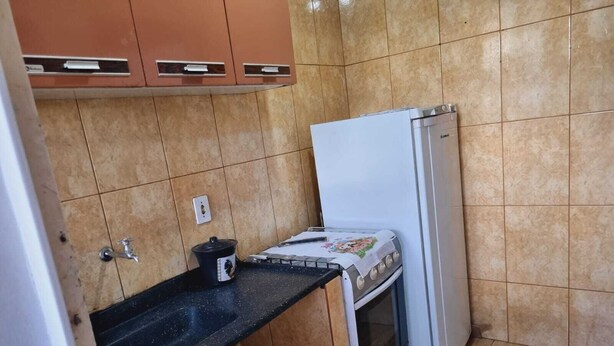 Una cocina compacta con estufa a gas, refrigerador blanco y un lavamanos pequeño.