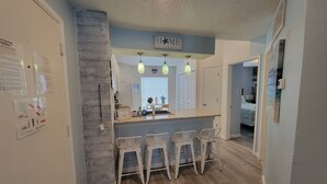 Une cuisine avec un coin bar, un plancher en bois et un panneau indiquant le mot « MAISON ».