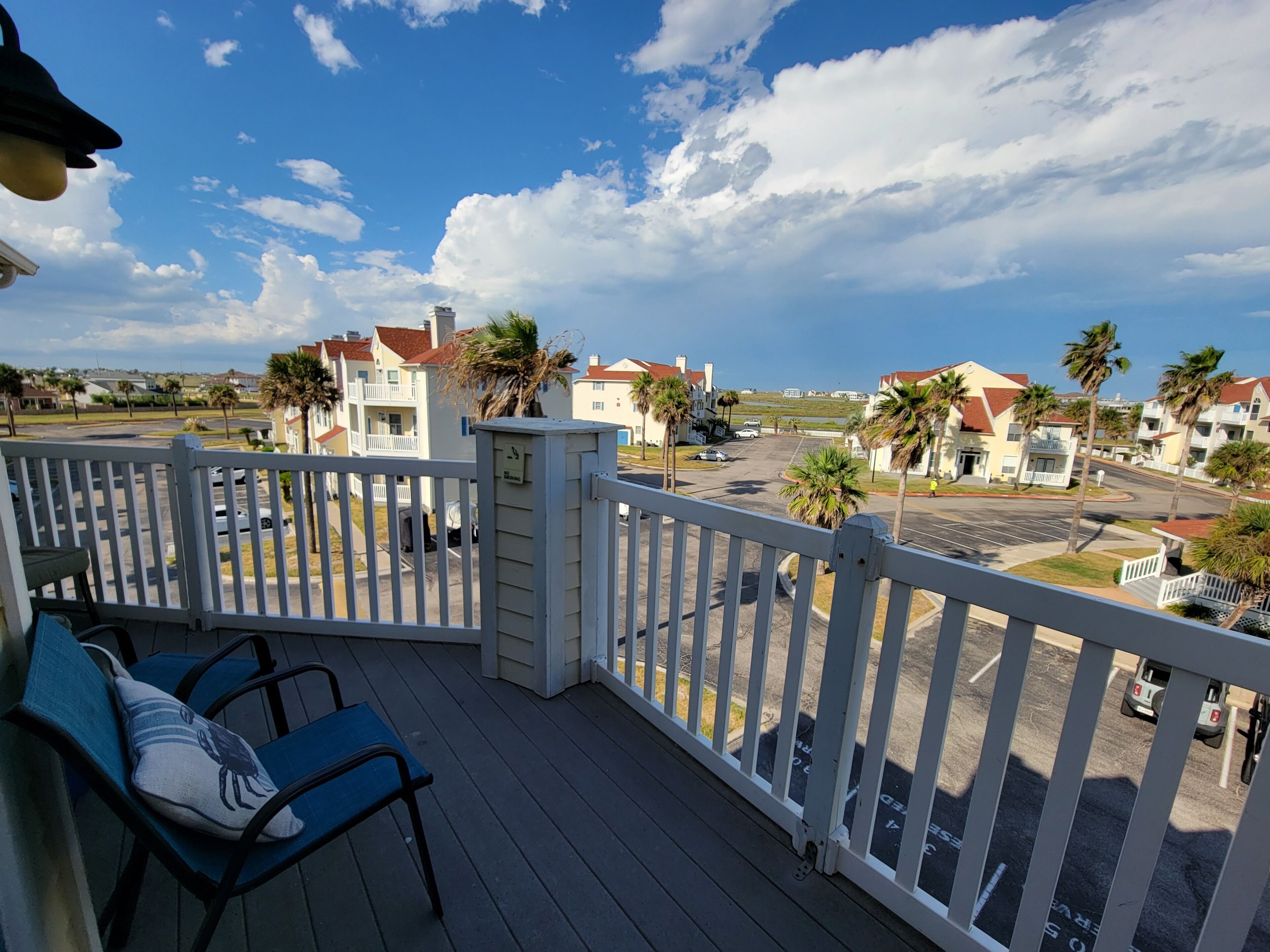A balcony with a view of a residential area, including houses and a parking lot.