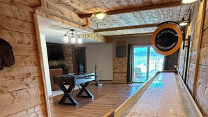 Ett rum med ett shuffleboard-bord, träpanel på väggarna och en öppen spis.