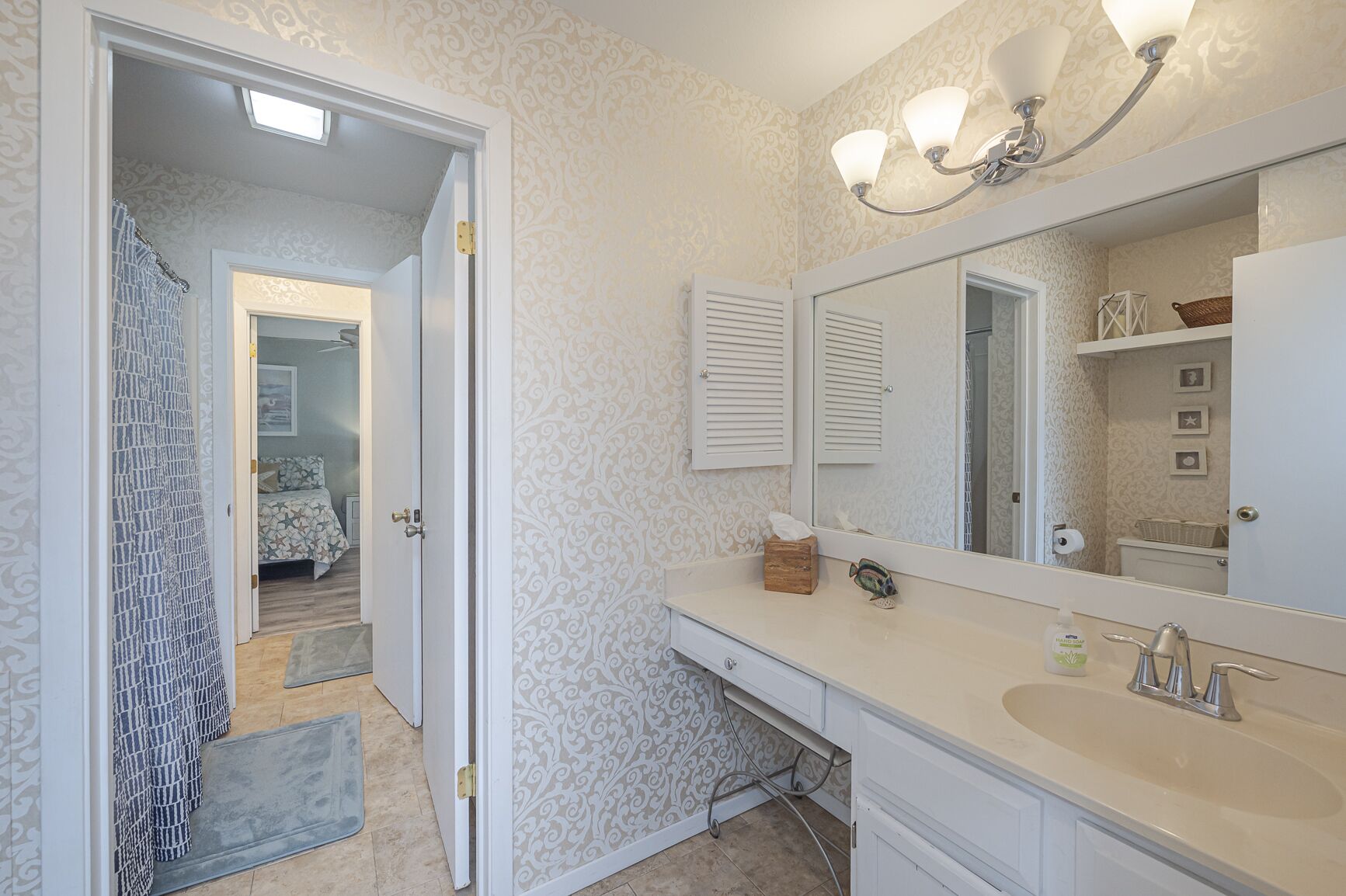 A bathroom with a large mirror, a sink, and a shower area.