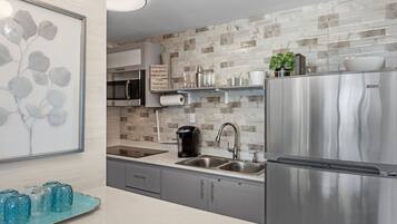 Uma cozinha moderna com eletrodomésticos de aço inoxidável, painel de fundo de mármore e uma bandeja decorativa azul.