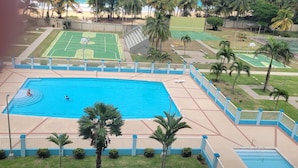 Una piscina con una cancha de baloncesto y una cancha de tenis al fondo.