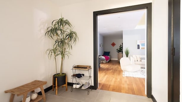 A hallway with a wooden bench, a potted plant, and a shoe rack. - Classy 2BR/1,5BA Boutique at Flushing! (Queens)