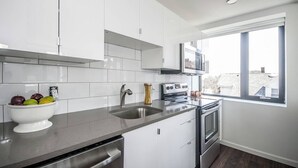 A modern kitchen with white cabinets, a stainless steel sink, and a built-in oven. - Newly furnished 1 bed, steps to Boston's restaurants, museums, hospitals, Fenway (Boston)