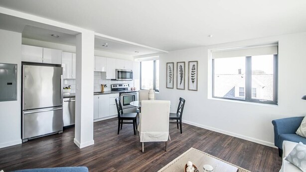 A modern kitchen with white cabinets, stainless steel appliances, and a dining area with a white table and chairs. - Newly furnished 1 bed, steps to Boston's restaurants, museums, hospitals, Fenway (Boston)