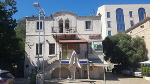 A two-story building with a stone facade, a balcony, and a small shop on the ground floor. - Haifa Vintage Rooms (Haifa)