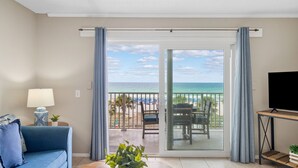 Une chambre avec balcon, un canapé, une télévision et vue sur la plage.