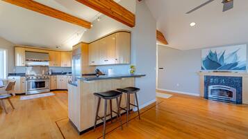 A modern kitchen with wooden beams, a central island with stools, and a built-in oven.