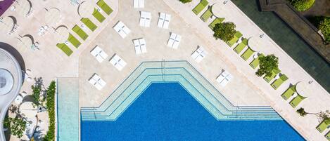 An aerial view of a pool area with multiple sun loungers and a central swimming pool.