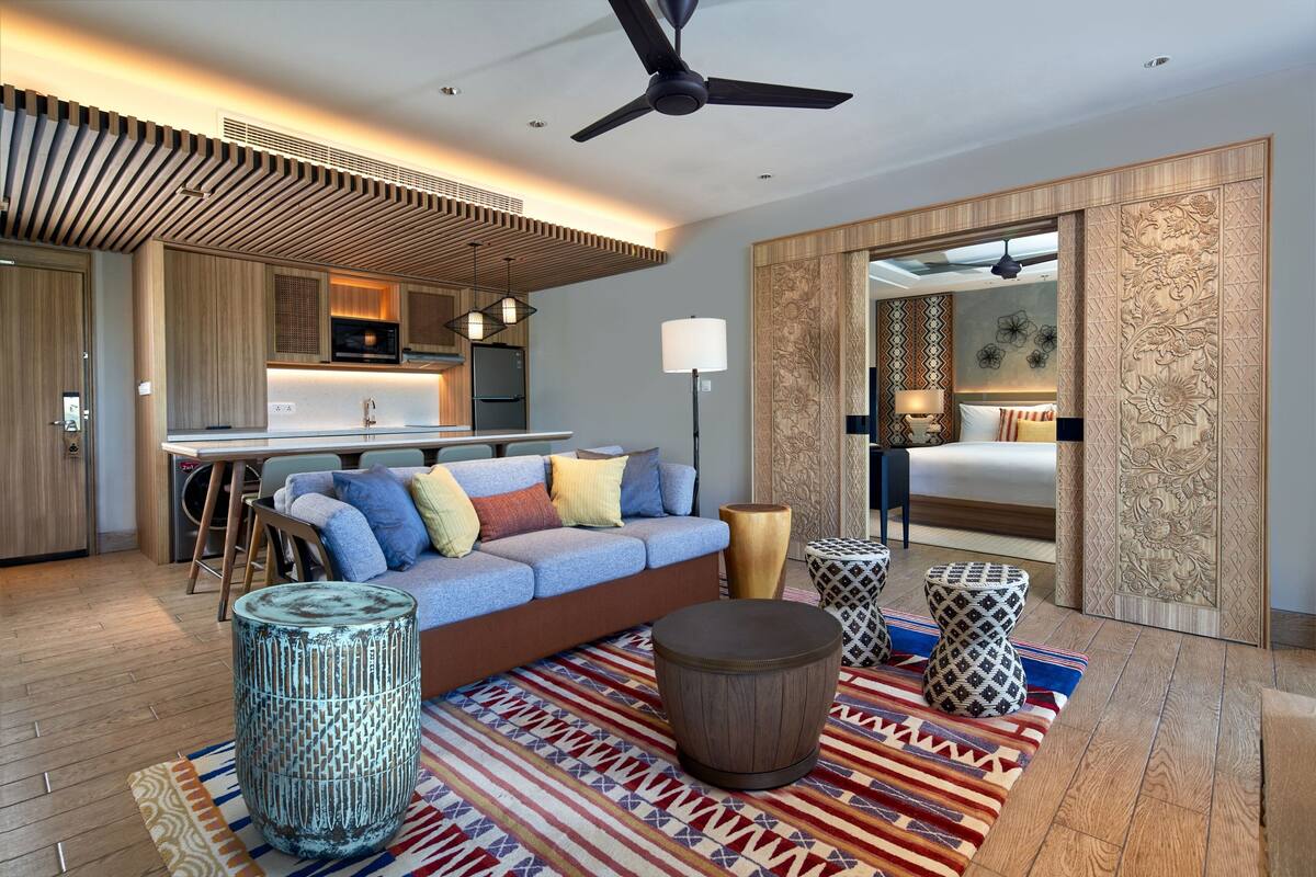 Un salon moderne avec un canapé, des poufs et un tapis à motifs.