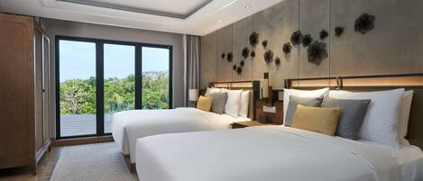 A modern hotel room with two beds, a ceiling fan, large windows, and a view of greenery.