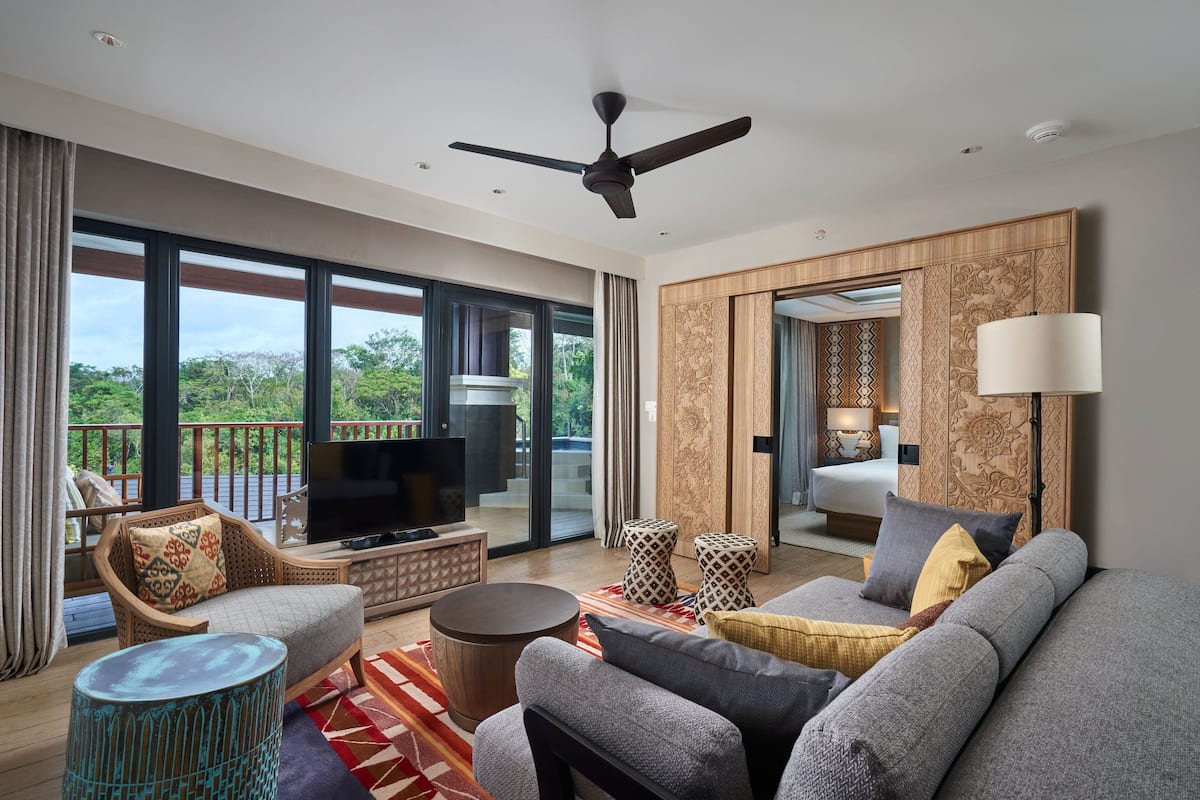 Un salon moderne avec un canapé, un téléviseur et un balcon offrant une vue agréable.