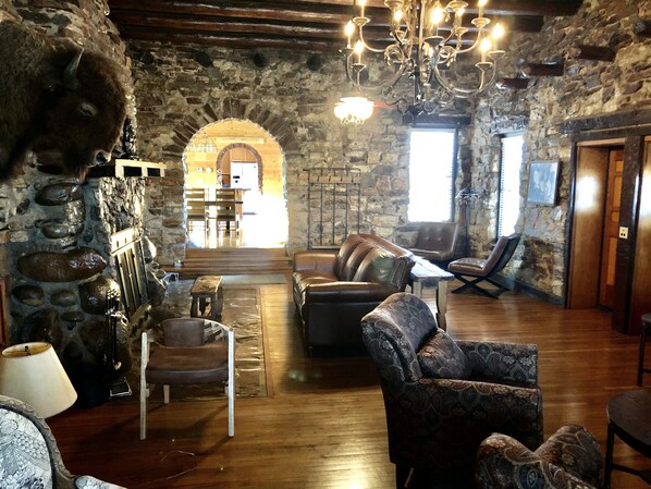 A rustic interior with stone walls, wooden furniture, and a chandelier. - 1926 Historic Dude Ranch Stone Lodge Home (Lake Montezuma)