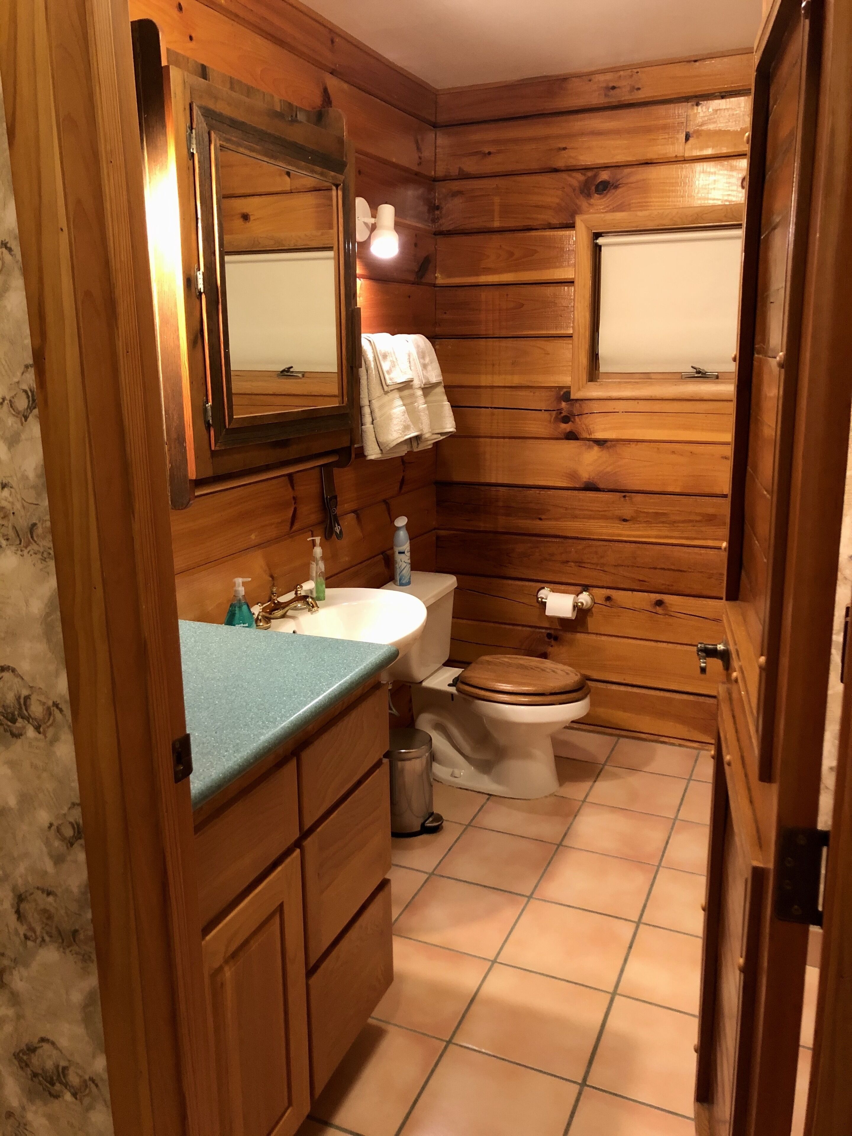 Un baño con paneles de madera, un lavabo, un inodoro y un espejo.