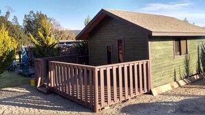 A small wooden cabin with a fenced deck, surrounded by trees and a clear sky. - Cabanas Ejido Santa Rosa Kilo78  Codigo 22766 (Santa Rosa)