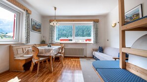 Una habitación acogedora con una mesa de madera, sillas, un sofá y una cama litera.