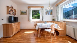 Un comedor con una mesa de madera, sillas y un televisor sobre un mueble.