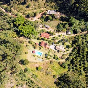 Oversigtsbillede af et boligområde med en swimmingpool, flere huse og grøn bevoksning omkring.