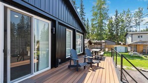 A modern building with large sliding glass doors, a wooden deck, and outdoor seating.