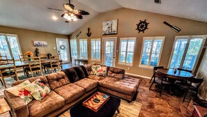 A spacious living room with a large sectional sofa, a dining area with a table and chairs, and a ceiling fan.