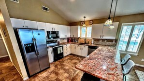 A spacious kitchen with a granite countertop, stainless steel appliances, and a large window providing natural light.