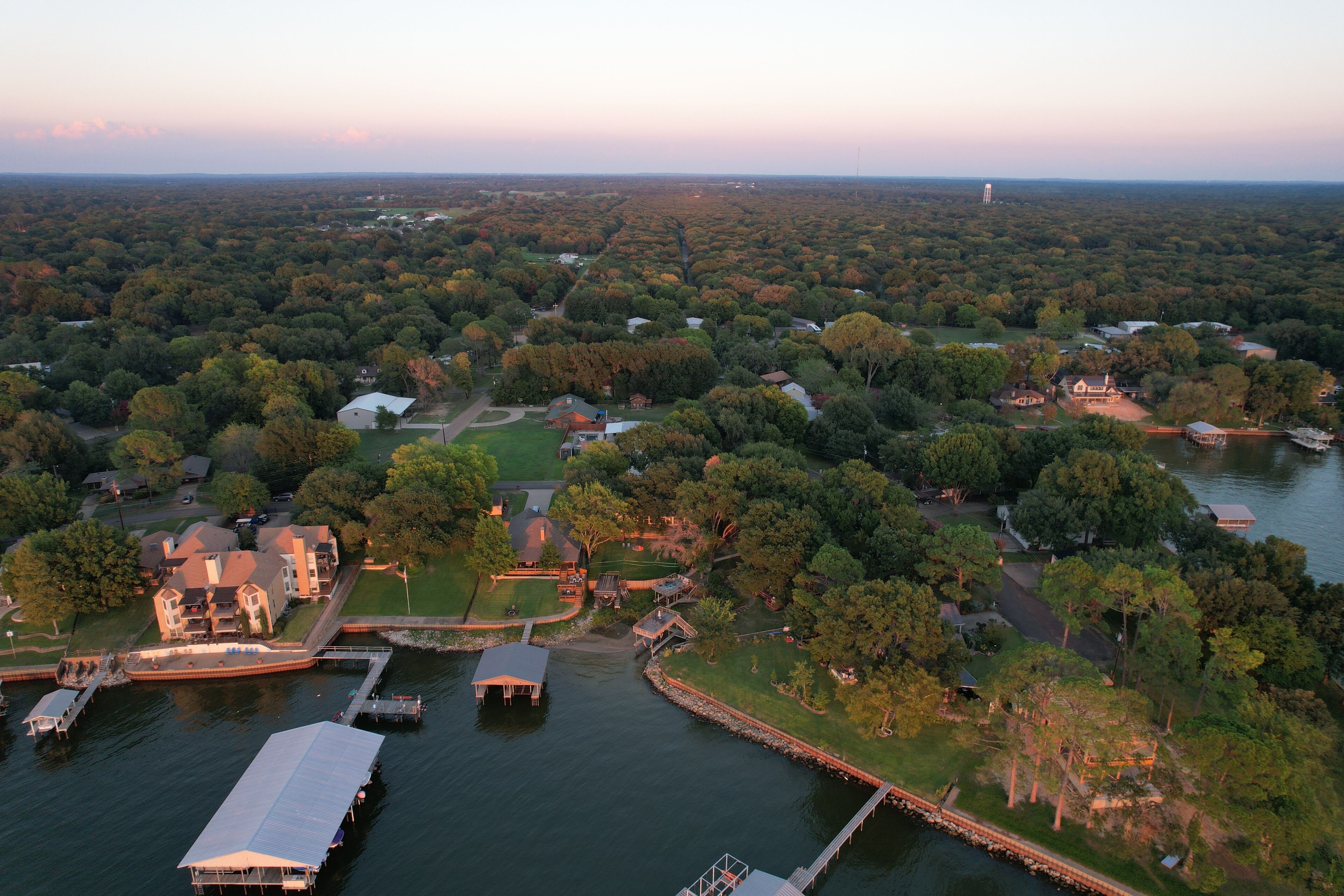 An aerial view of a lakeside residential area with multiple houses, docks, and a large boat dock.