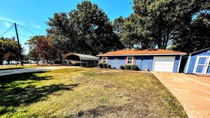 A residential house with a garage, a covered patio, and a well-maintained lawn.