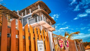 A hotel entrance with a wooden fence and a sign indicating 'Registered Guests Only'. - Costa Nube (Caye Caulker)
