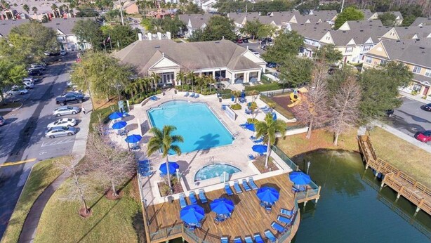 A resort with a large swimming pool, a wooden deck, and a dock over water.