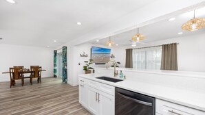 A modern kitchen with white cabinetry, a large island with a sink, and pendant lighting. - Spacious & Fun Family Gem / Pool, Beach, Blue Jays (Palm Harbor)