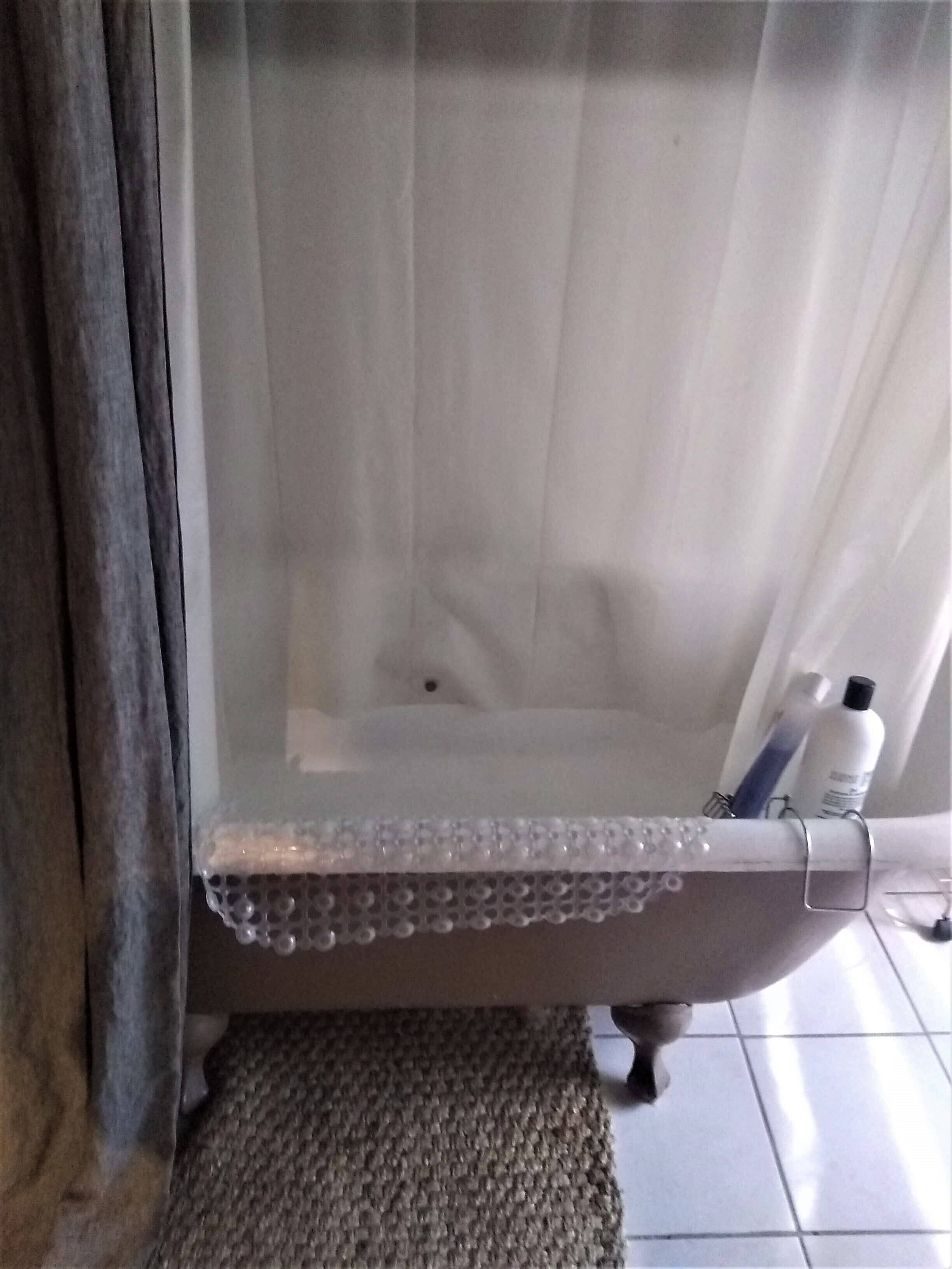 A bathroom with a shower curtain, a towel rack, and toiletries on the wall.