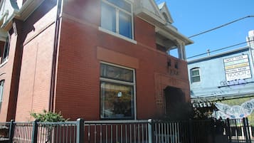 A red brick building with a large window and a small door. There is a sign on the building that reads "Fancy Tiger."