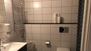 A small bathroom with a white sink, a toilet, and a shower area. - Apartment in Årsta Stockholm 237 (Arsta)