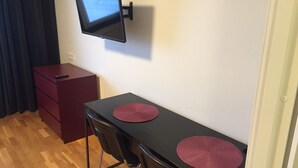 A small room with a TV mounted on the wall, a desk with two chairs, and a red filing cabinet. - Apartment in Årsta Stockholm 237 (Arsta)